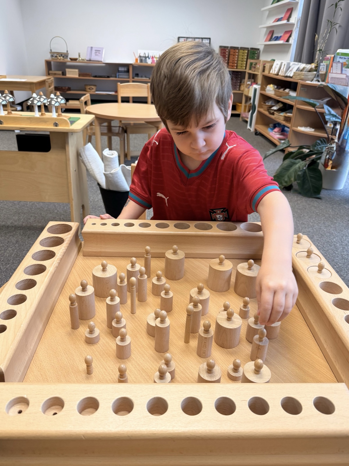 Primary child working with the knobbed cylinders
