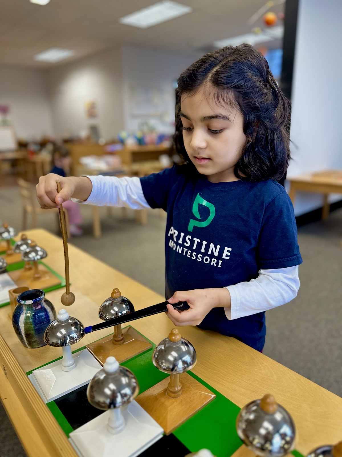 child playing the Montessori bells, sensorial work